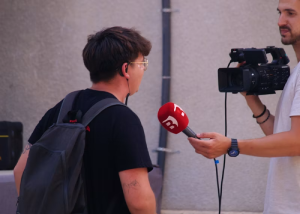 Young man being interviewed with a microphone held up to him outdoors